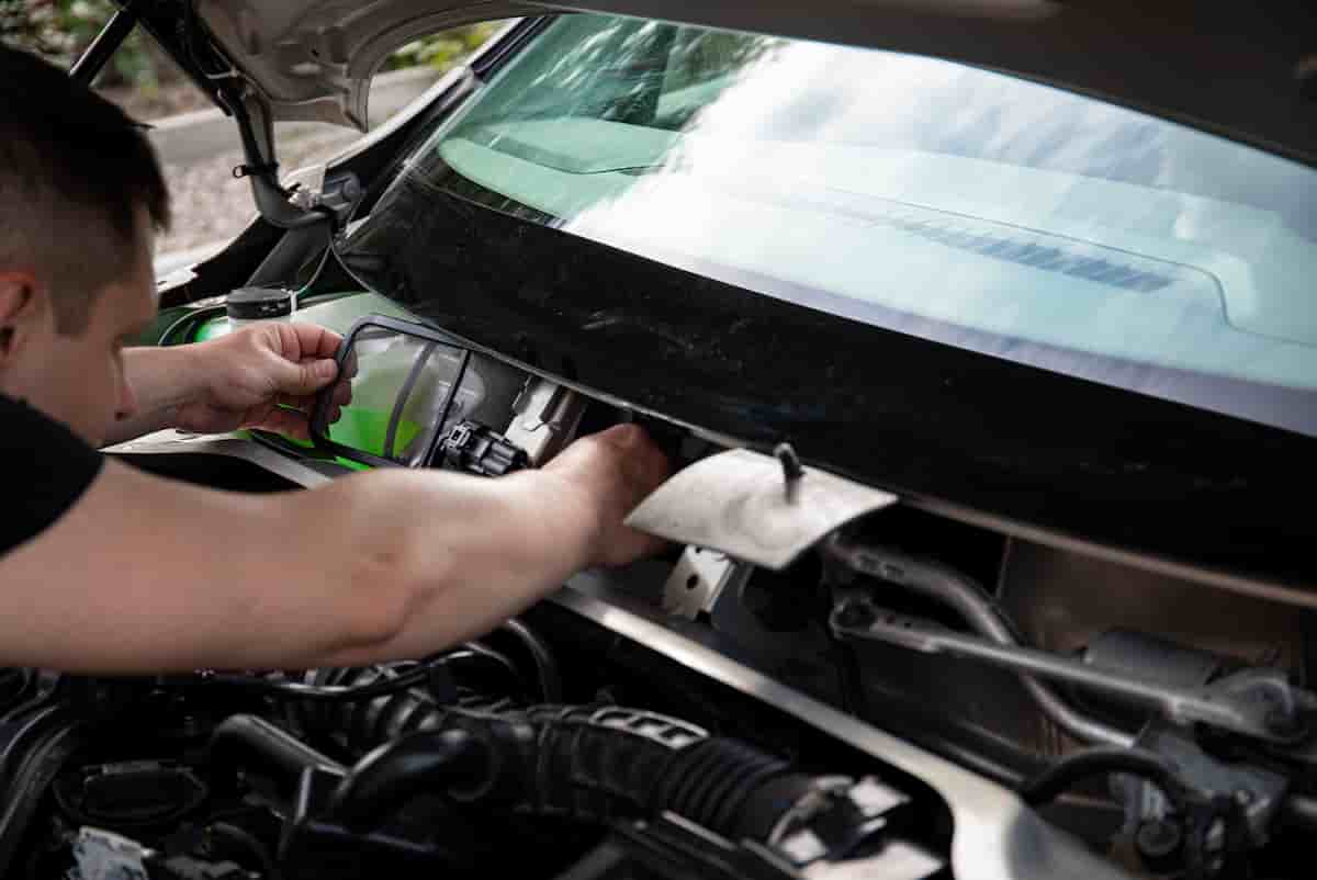 Mechanic inspecting under a used car with a flashlight